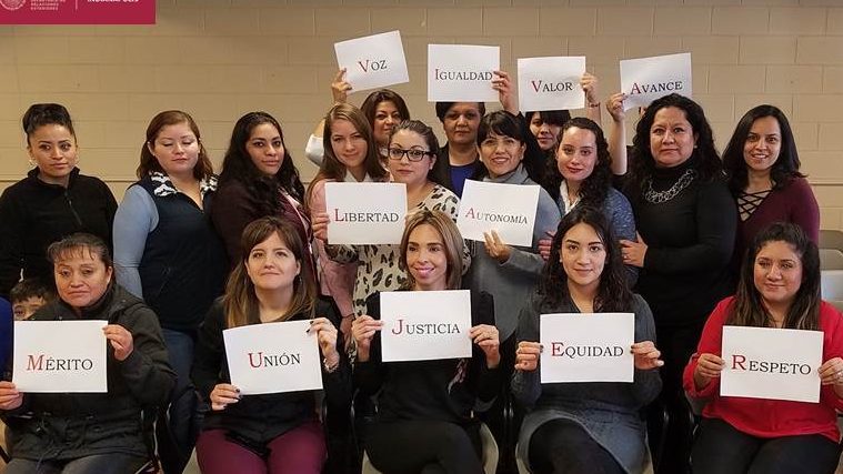 A group of women hold up signs with empowering words.